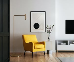 Inspiraatiokuvaesimerkki. Keltainen nojatuoli, lamppu, taulu ja pöytä muodostavat harmonisen kokonaisuuden.