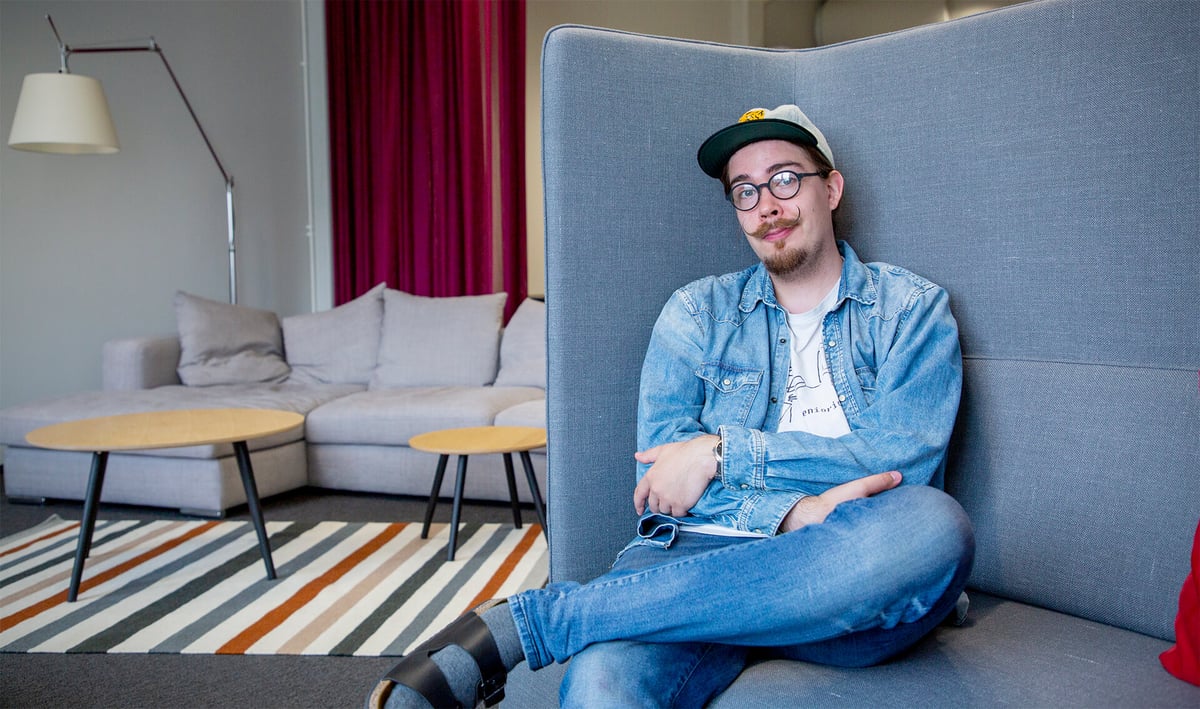 Arttu Rantakärkkä istuu sohvan nurkassa. Taustalla taukotila, jossa sohva ja kaksi sohvapöytää.
