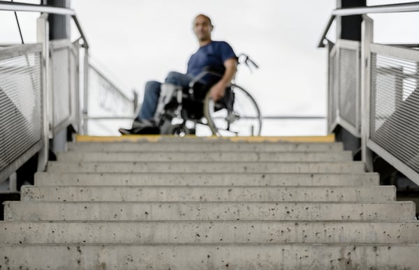 Mies istuu pyörätuolissa, edessä on portaat